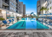 Thumbnail 22 of 48 - a swimming pool at an apartment building with a pool and lounge chairs