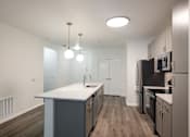Thumbnail 21 of 35 - A kitchen with a white counter top and black appliances.