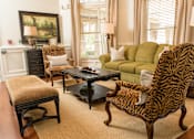 Thumbnail 6 of 18 - A zebra print chair sits in a living room with a green couch and a coffee table.