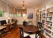 Thumbnail 2 of 18 - A room with a desk, chairs, and a bookshelf filled with books.