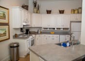 Thumbnail 12 of 23 - A kitchen with white cabinets and a marble countertop.