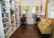 Thumbnail 5 of 23 - A room with a yellow couch, two laptops, and a bookshelf filled with books.
