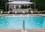Thumbnail 15 of 23 - A pool with a white umbrella and a stone wall in the background.