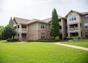 Thumbnail 21 of 23 - Apartment complex with a green lawn in front.