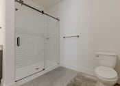 Thumbnail 12 of 33 - A white toilet sits next to a walk-in shower with a glass door.