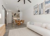 Thumbnail 6 of 33 - A white couch sits in a room with a table and chairs.
