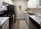 Thumbnail 10 of 31 - a kitchen with white cabinets and a black stove top oven  at Waterview at Rocky Point, Tampa