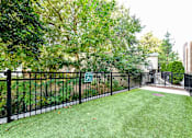 Thumbnail 55 of 57 - Decatur, GA Apartments Near Agnes Scott College - ARLO - Fenced Dog Park With Manicured Grass, Waste Disposal Area, And Surrounding Lush Greenery.