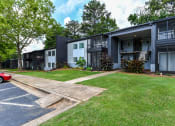 Thumbnail 9 of 13 - a row of apartment buildings with a grassy yard and trees in the background