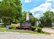 Thumbnail 13 of 13 - a sign that says the flats in front of trees and bushes