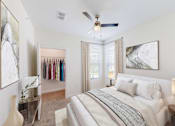 Thumbnail 41 of 50 - A bedroom with a large bed, a ceiling fan, and a closet with clothes hanging.