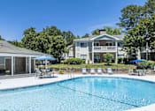 Thumbnail 1 of 36 - A swimming pool in front of a house with a blue umbrella.