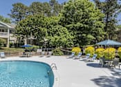 Thumbnail 21 of 36 - A swimming pool surrounded by trees and chairs.