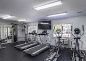 Thumbnail 5 of 36 - A spacious home gym with treadmills, elliptical machines, and a television.