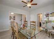 Thumbnail 7 of 14 - A dining room with a glass table and chairs.
