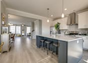 Thumbnail 4 of 14 - A modern kitchen with a large island and stainless steel appliances.