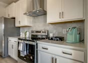 Thumbnail 3 of 14 - A kitchen with a stove, oven, and refrigerator.