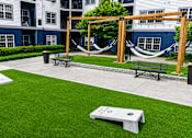Thumbnail 27 of 29 - A hammock is suspended between two wooden posts in a grassy courtyard.