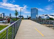Thumbnail 29 of 29 - A walkway with a metal railing leads to a city skyline.