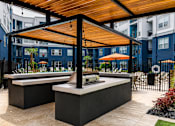Thumbnail 26 of 29 - A modern outdoor kitchen area with a wooden roof and black countertops.