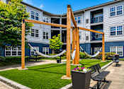 Thumbnail 24 of 29 - A playground with a slide and a hammock in front of apartment buildings.