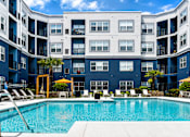 Thumbnail 23 of 29 - A large swimming pool in front of a blue building with white balconies.