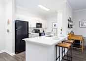 Thumbnail 2 of 29 - A black refrigerator is in a kitchen with white countertops.