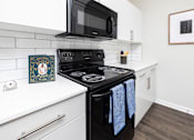 Thumbnail 4 of 29 - A black stove top oven with blue towels hanging on it.