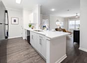Thumbnail 6 of 29 - A modern kitchen with white cabinets and a black refrigerator.