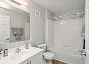 Thumbnail 9 of 13 - A white bathroom with a toilet, sink, and bathtub.
