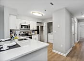 Thumbnail 7 of 13 - A modern kitchen with white countertops and stainless steel appliances.