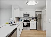 Thumbnail 6 of 13 - A modern kitchen with white cabinets and stainless steel appliances.