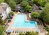 Thumbnail 27 of 30 - An aerial view of a swimming pool surrounded by trees and umbrellas.