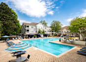 Thumbnail 1 of 30 - A large swimming pool surrounded by lounge chairs and umbrellas.