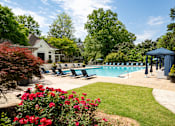 Thumbnail 26 of 30 - A pool surrounded by a lawn and trees with a house in the background.