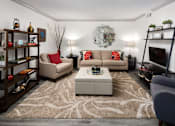 Thumbnail 7 of 30 - A living room with a beige sofa, a grey armchair, a coffee table, and a television.