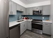 Thumbnail 3 of 30 - A kitchen with a stainless steel refrigerator, microwave, oven, and dishwasher.