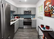 Thumbnail 2 of 30 - A modern kitchen with a refrigerator, microwave, oven, and dishwasher.