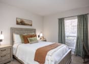Thumbnail 13 of 31 - A bedroom with a large bed, a nightstand with a lamp, and a painting on the wall.