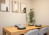 Thumbnail 6 of 31 - A dining table with chairs, bowls, and a vase with a plant.