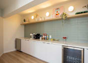 Thumbnail 19 of 31 - A kitchen with a white counter and a black fridge.
