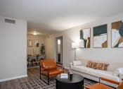 Thumbnail 11 of 31 - A living room with a white couch, orange chairs, and a black coffee table.