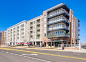 Thumbnail 1 of 22 - A large, modern apartment building with balconies and multiple stories.