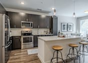 Thumbnail 3 of 26 - A modern kitchen with dark wood cabinets and stainless steel appliances.