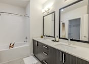 Thumbnail 11 of 26 - A modern bathroom with a white tub, sink, and mirror.