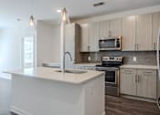 Thumbnail 13 of 26 - A modern kitchen with a white island and wooden cabinets.