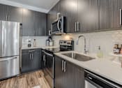 Thumbnail 2 of 26 - A modern kitchen with dark wood cabinets and stainless steel appliances.
