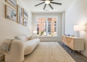 Thumbnail 5 of 33 - A living room with a white couch and a ceiling fan.