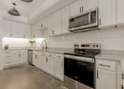 Thumbnail 4 of 33 - A modern kitchen with white cabinets and stainless steel appliances.