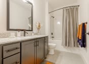 Thumbnail 10 of 33 - A bathroom with a sink, mirror, toilet, and shower.